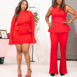 Two women in red outfits pose confidently in a studio, one in a red dress with long sleeves and heels, the other in a red sleeveless top with wide-leg pants.